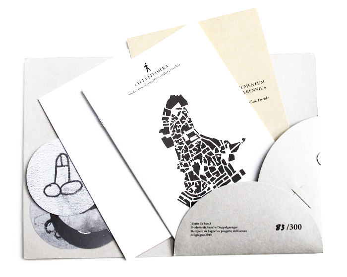 Set of printed booklets and cards fanned out from a grey card sleeve, including a cover titled "Città Effimera" with a black silhouette map, a numbered edition "83/300" visible on the sleeve.