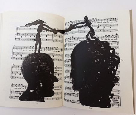 Open sheet music book with two large black silhouette heads printed over the pages, each topped by a small human figure, the two figures holding hands across the spread.