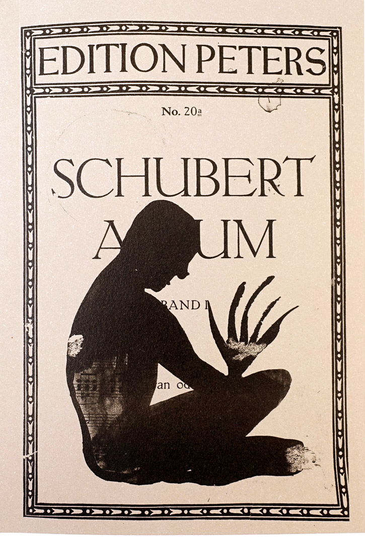 Four-panel view of an open book titled "Franz Schubert" with a black silhouette illustration on its title page, alongside other spreads showing black ink drawings of a profile face and running animal figures added over printed sheet music.