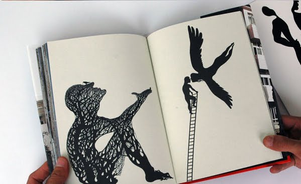 Open art book spread held open by two hands, showing a black silhouette of a seated figure made of branching lines on the left page, and a figure climbing a ladder reaching toward a large bird in flight on the right page.