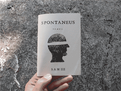 Booklet titled "SPONTANEUS TOMO I, SAM III" held in a hand against a textured stone surface, showing a black silhouette of a helmeted head in profile.