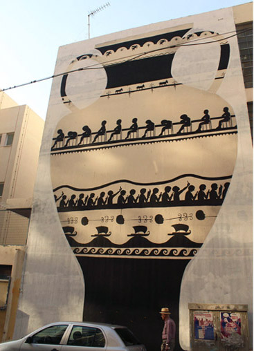 Full building facade mural of a giant black-figure Greek amphora, showing a row of seated figures and its decorative bands, a car and a pedestrian at street level.