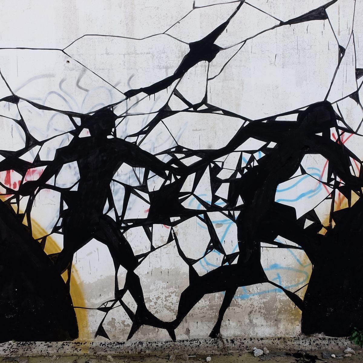 Detail of the amphora mural showing two black silhouetted figures breaking through a web of fractured lines on a weathered white wall, faint colored graffiti scribbles beneath.